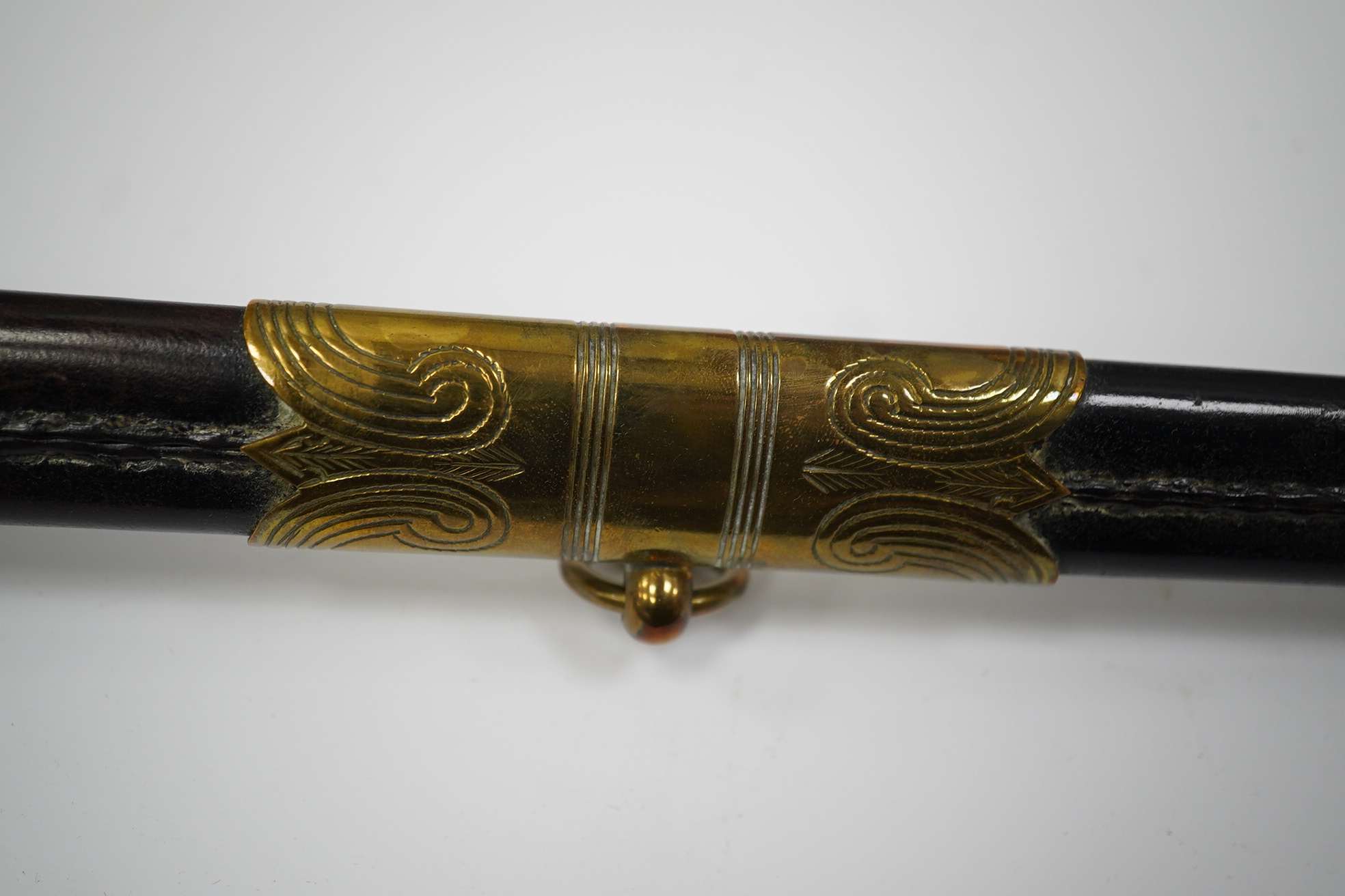 An 1846 pattern naval officer’s sword by Gieves, with folding thumb guard and knot, in its leather scabbard with brass mounts. Together with its outer soft leather cover. Condition - fair, notable wear to grip.